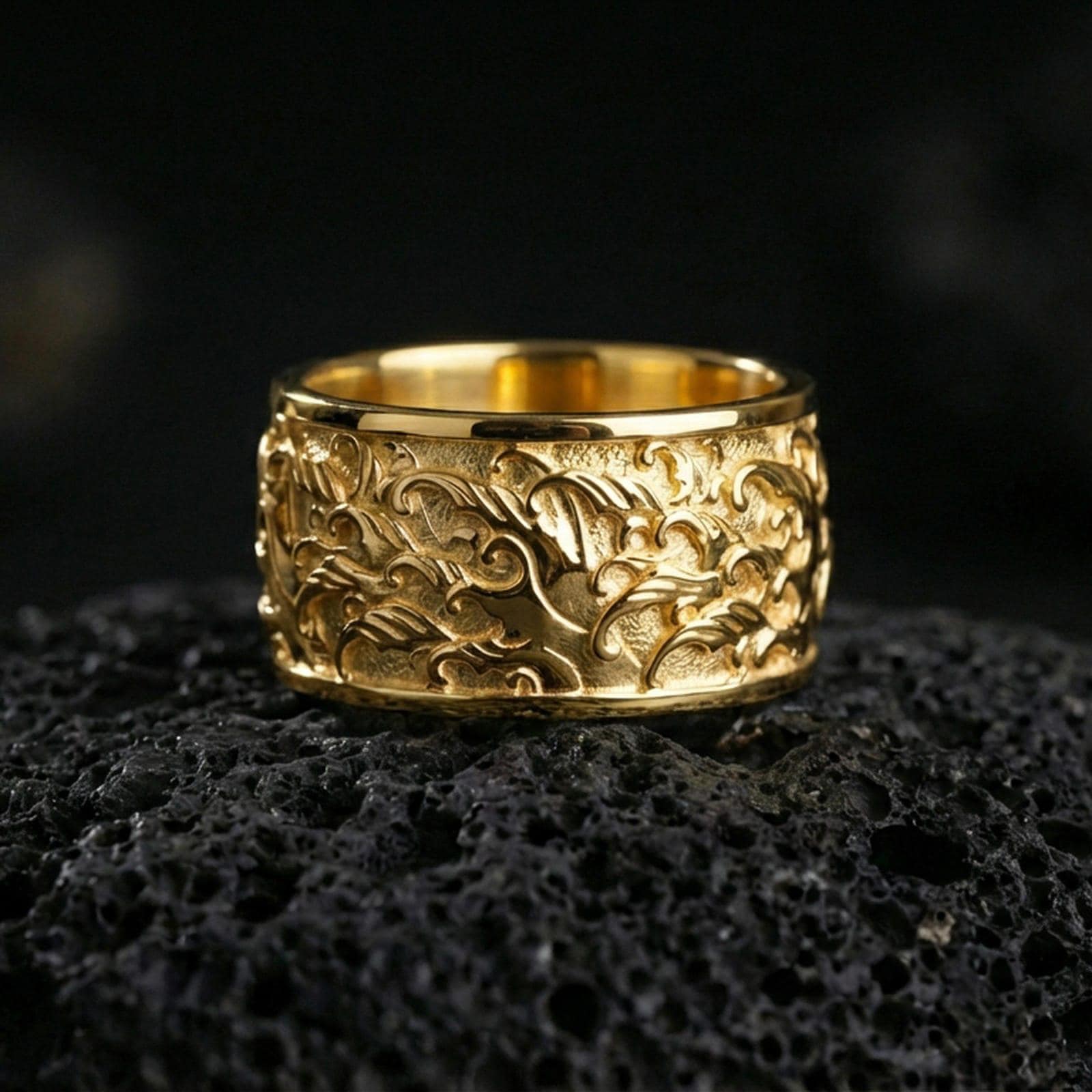 Gold plated swirling flames band ring on volcanic rock, detailed fire wave relief with bold sculpted depth, luxury jewelry product photography.