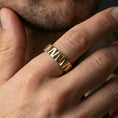 Load image into Gallery viewer, Gold plated chevron-faceted band worn on finger, sharp triangular grooves and reflective highlights, premium lifestyle jewelry shot.
