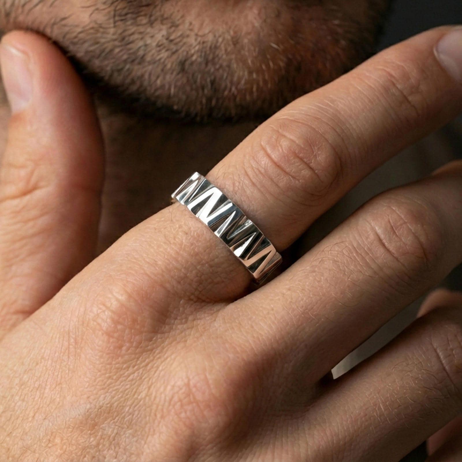 Polished silver geometric wedge band ring on finger, crisp angular facets and brushed finish, natural everyday wear photo.