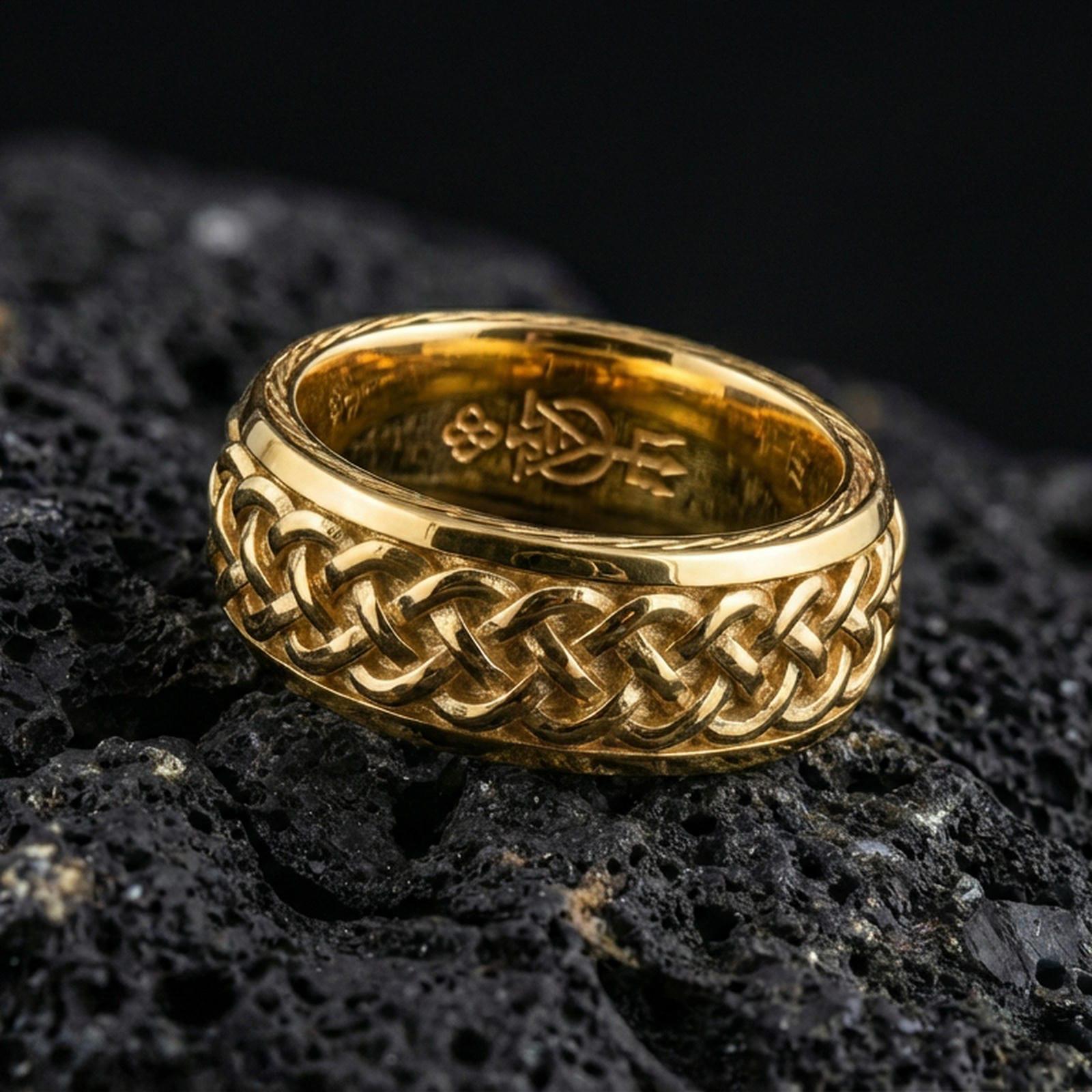 Gold plated Celtic knot woven band ring on volcanic rock, bold raised braid texture with high-contrast depth, luxury studio macro image.