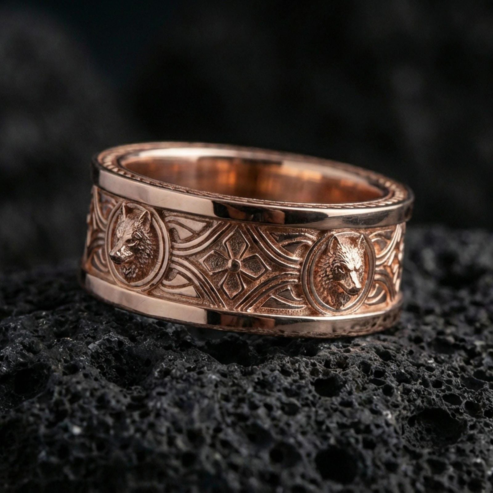 Rose gold plated wolf Celtic band on black volcanic stone, detailed wolf medallions with warm shine and high-relief texture, elegant product photo.