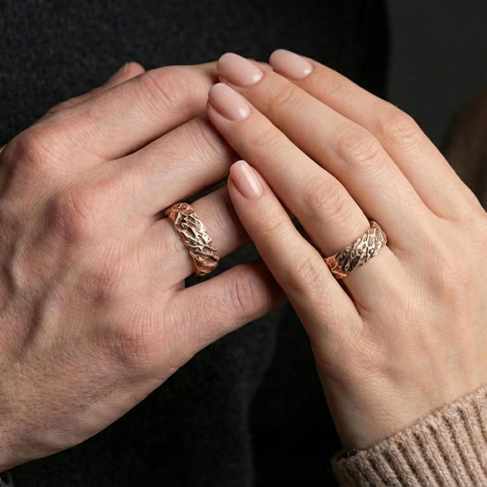 Rose gold plated hammered texture ring worn on finger, warm sheen with sculpted rock relief, refined lifestyle close-up.