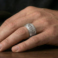Load image into Gallery viewer, Polished silver Celtic braid iron cross ring worn on finger, clean comfort fit with high-contrast engraved knotwork in natural light.
