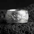 Load image into Gallery viewer, Polished silver Celtic braid band ring on volcanic rock, crisp engraved knotwork and iron cross emblem captured in sharp macro focus.
