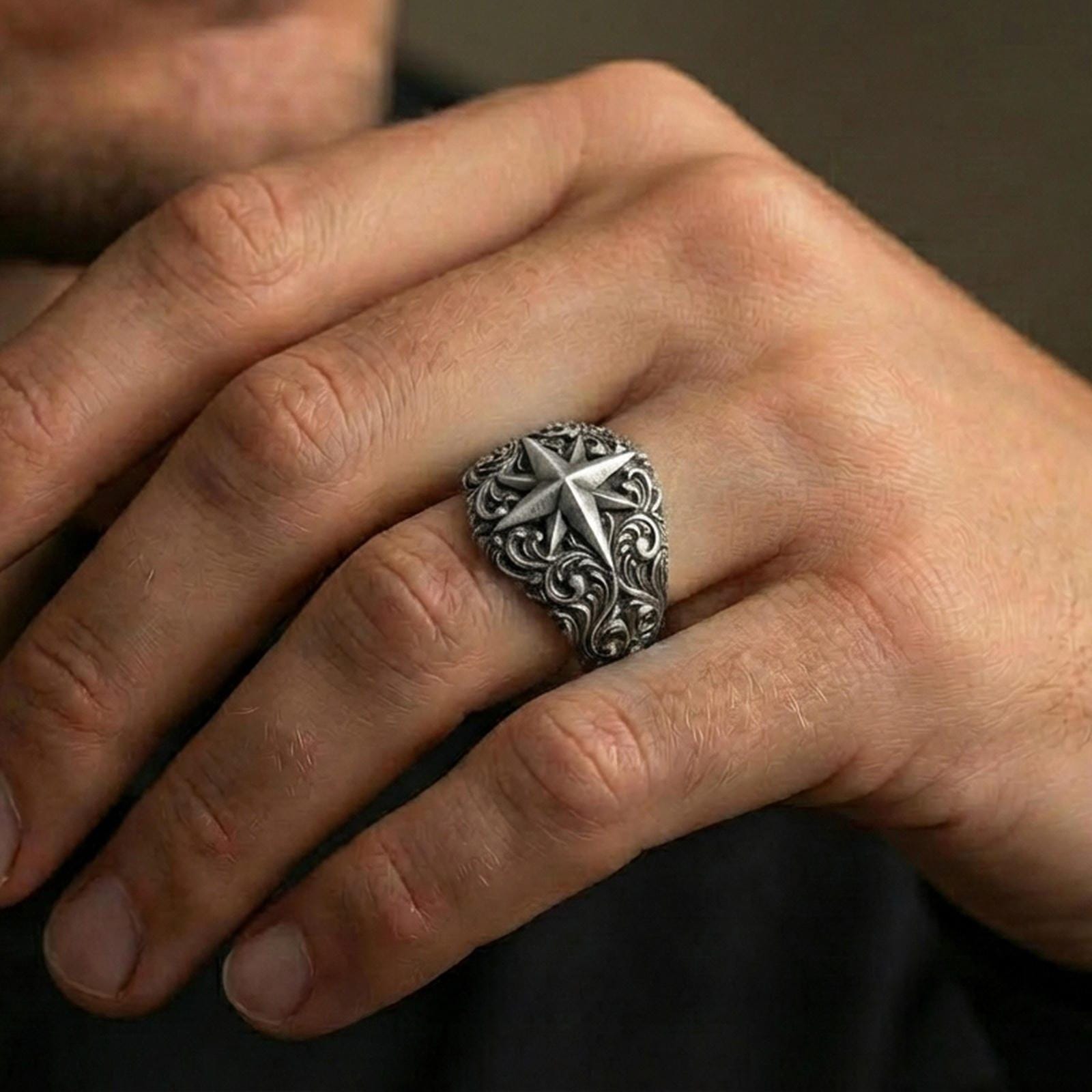 Oxidized sterling silver North Star compass ring worn on finger, darkened relief accentuating the carved star and ornate scrollwork shoulders.