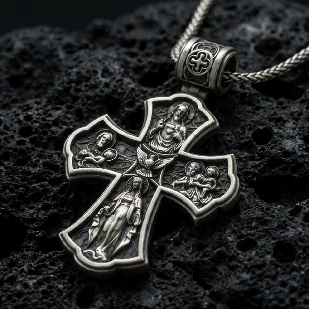Holy Trinity cross pendant on black volcanic stone with deep oxidized contrast and crisp relief details.