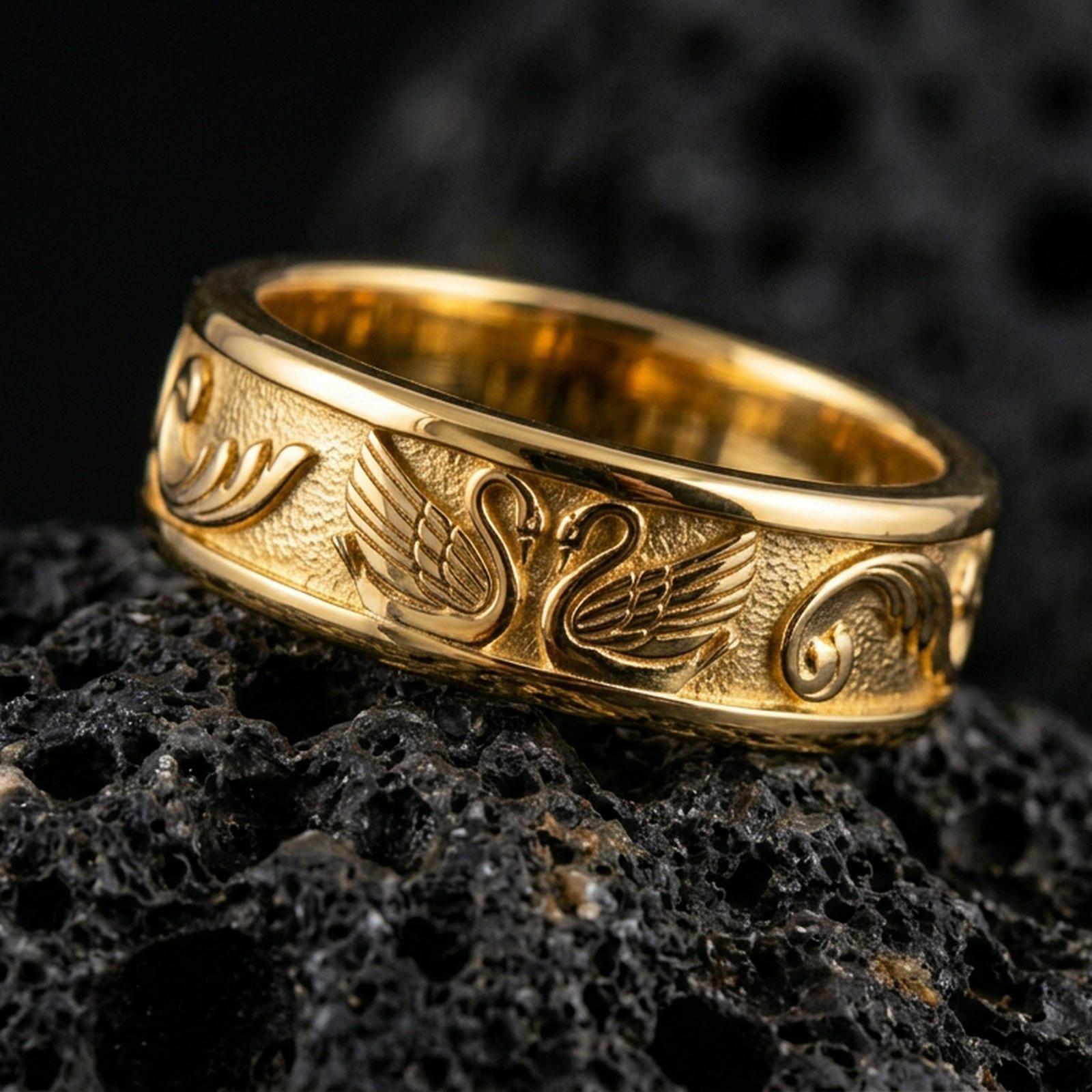 Swan engraved ring displayed on volcanic rock with a gold plated finish, highlighting the wing lines and smooth rounded band.