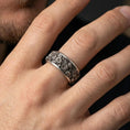 Load image into Gallery viewer, Oxidized sterling silver daisy spinner ring worn on a finger, showcasing the rotating band and high-relief flower engraving.

