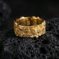 Load image into Gallery viewer, Floral relief ring displayed on volcanic rock with a gold plated finish, emphasizing the layered petals and sculpted leaves.
