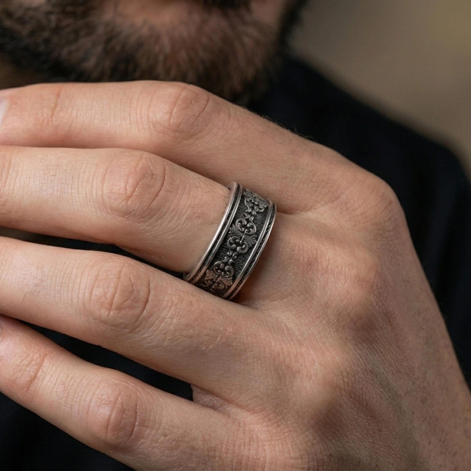 Oxidized sterling silver scroll ring worn on a finger, showcasing the carved filigree pattern and classic comfort-fit band shape.