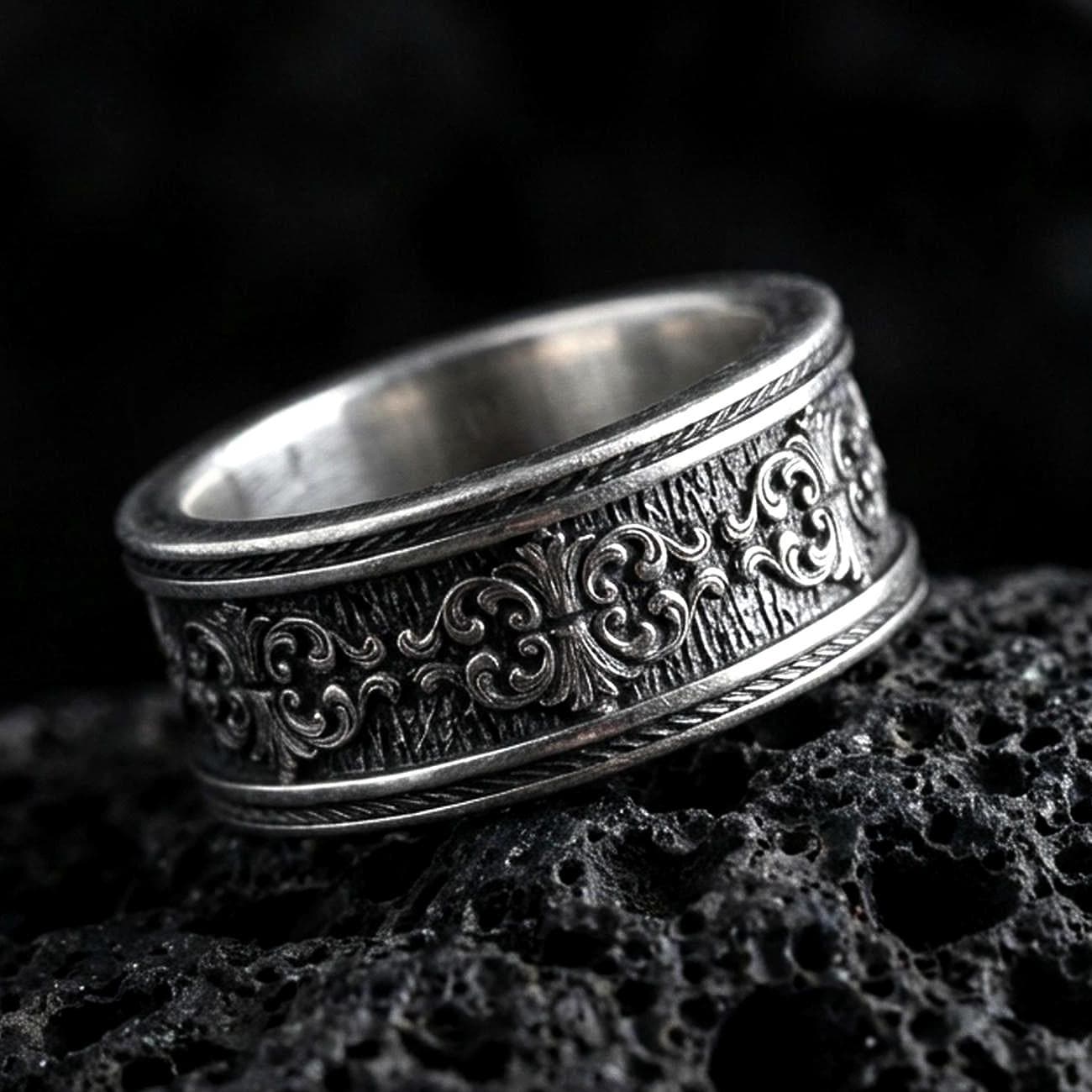 Sterling silver ornate scroll ring photographed on volcanic rock with oxidized contrast highlighting the engraved filigree and textured center band.
