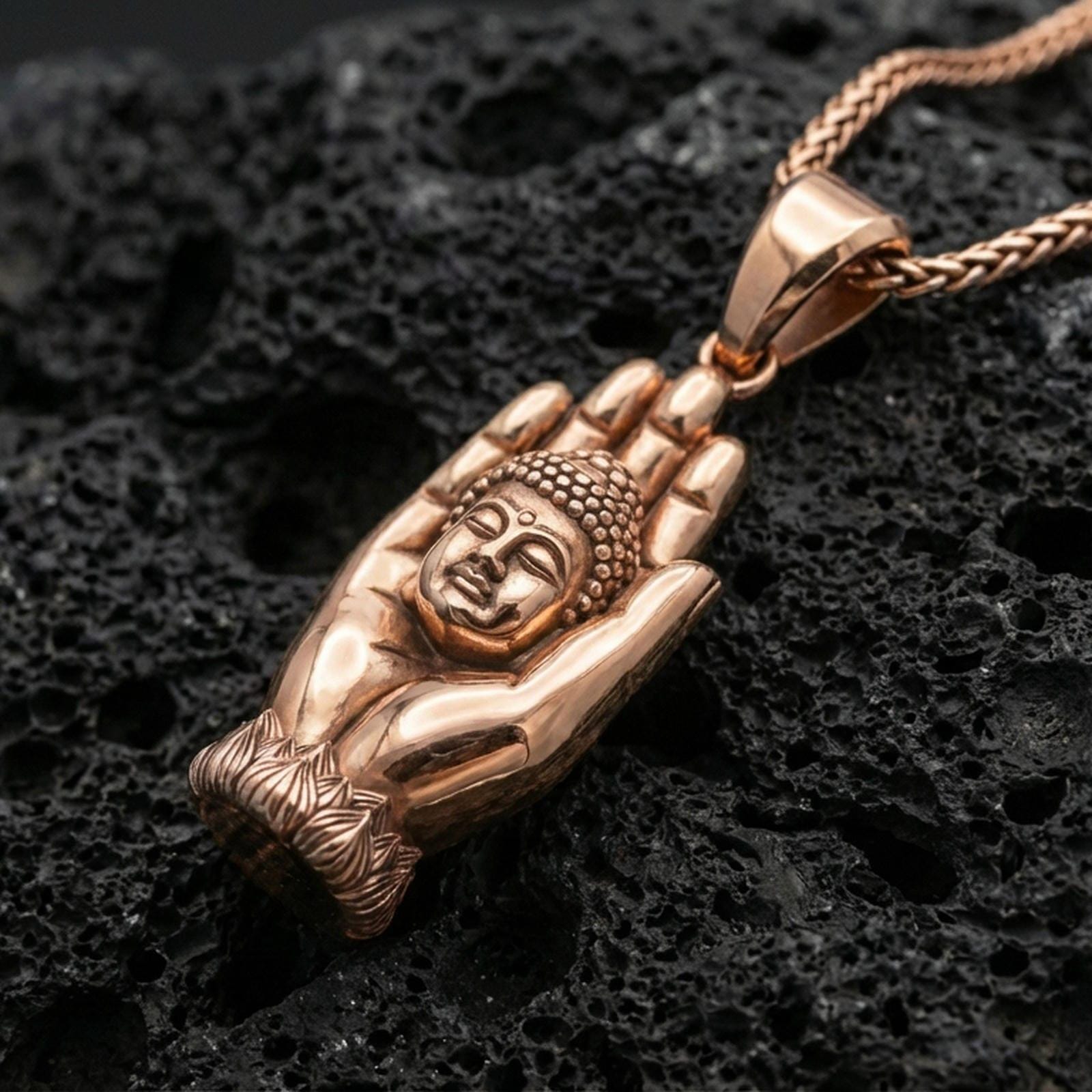 Buddha hand pendant on volcanic stone in a rose gold plated look, giving warm tone to the Buddha face and hand silhouette.