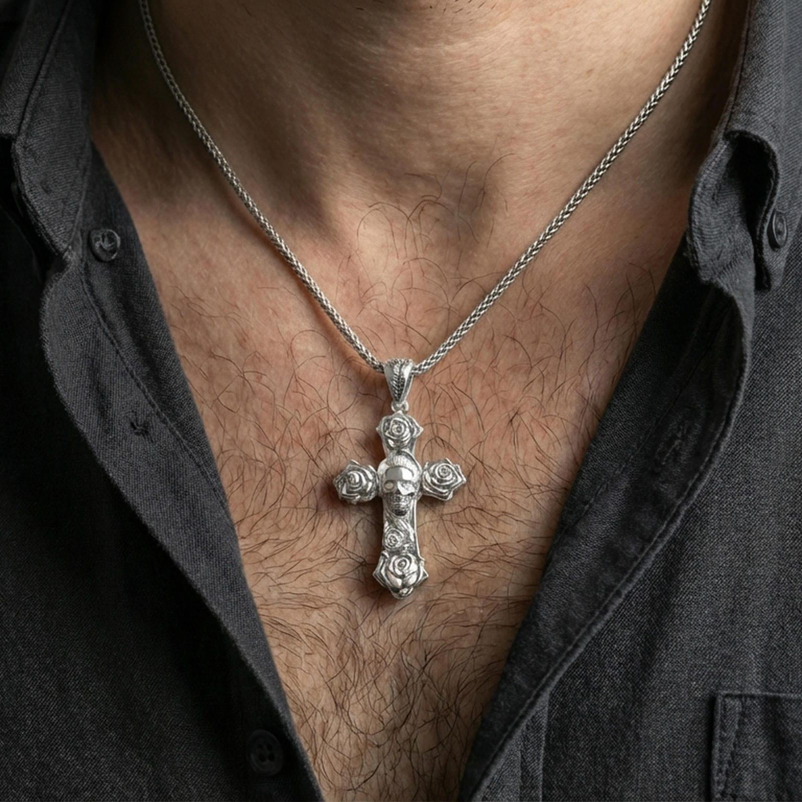 Polished silver floral cross pendant with masked portrait worn on the neck in a close lifestyle frame, highlighting the pendant against the chest