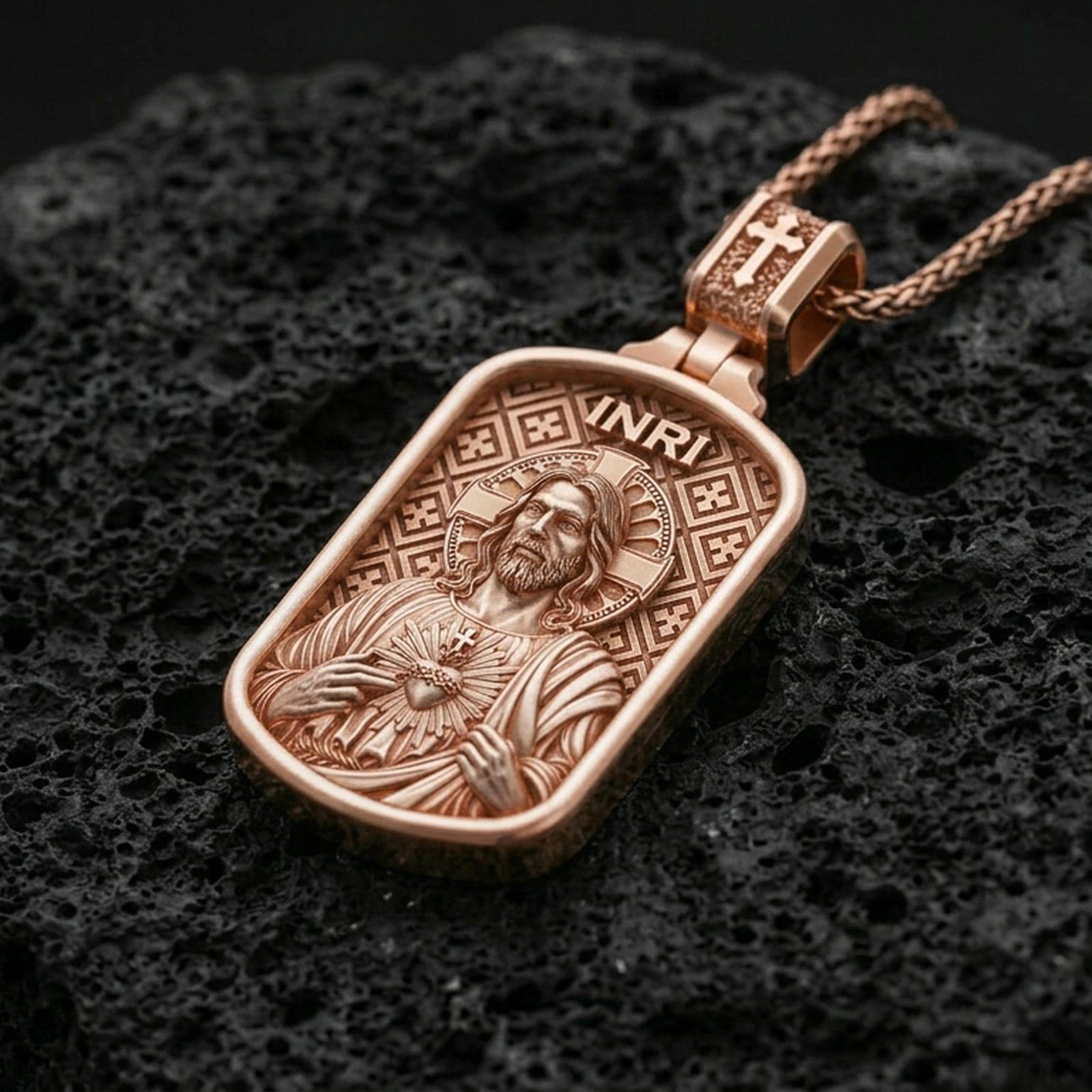 Rose gold plated devotional Jesus pendant with Sacred Heart motif, halo detail, and framed silhouette resting on volcanic rock in an elegant close-up product presentation