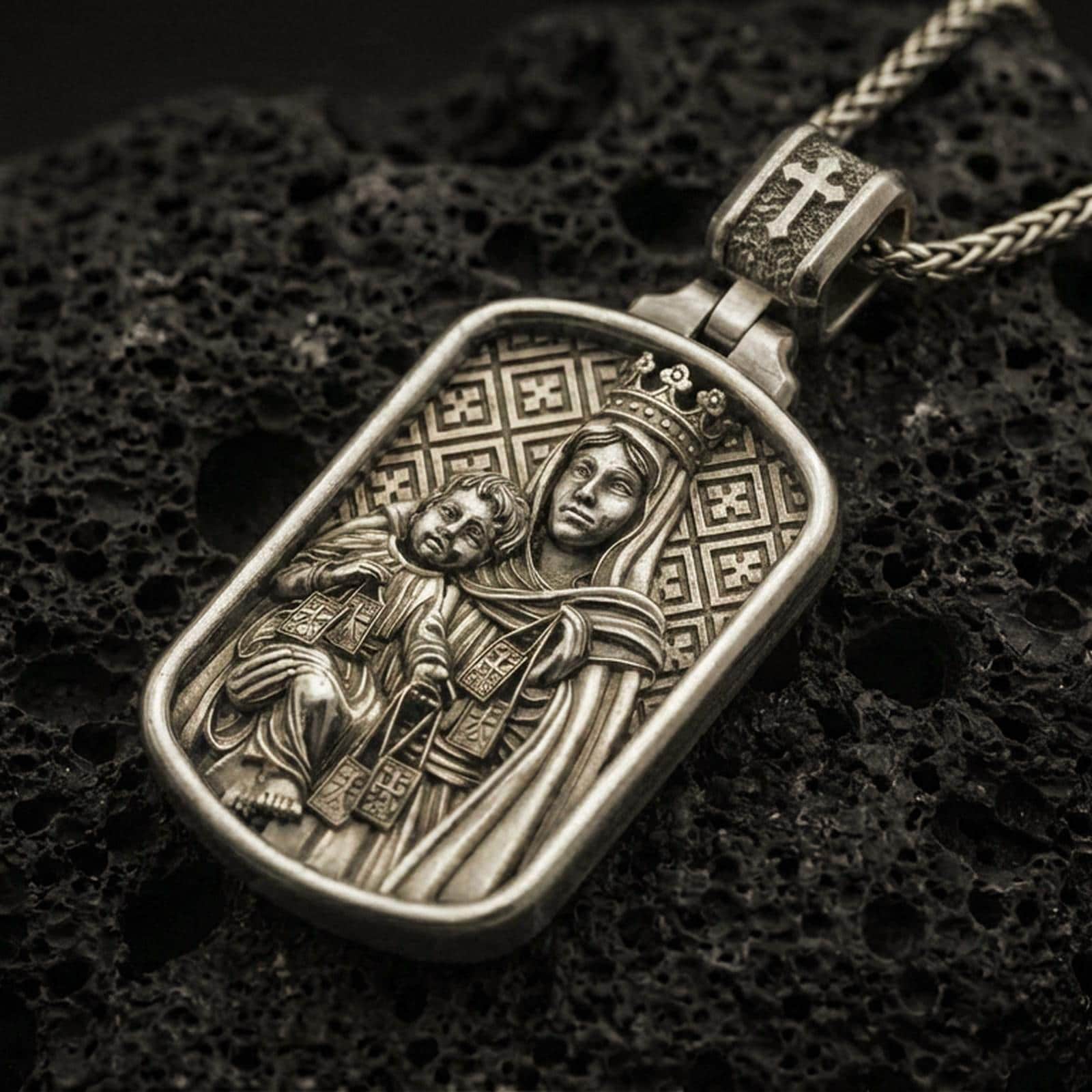 Bronze Virgin Mary and Child pendant with crowned Madonna relief displayed on dark volcanic rock in a close-up luxury jewelry composition