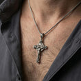 Load image into Gallery viewer, Oxidized crucifix pendant with Jesus figure worn on the neck in a lifestyle jewelry shot, styled against the chest for a bold and devotional look

