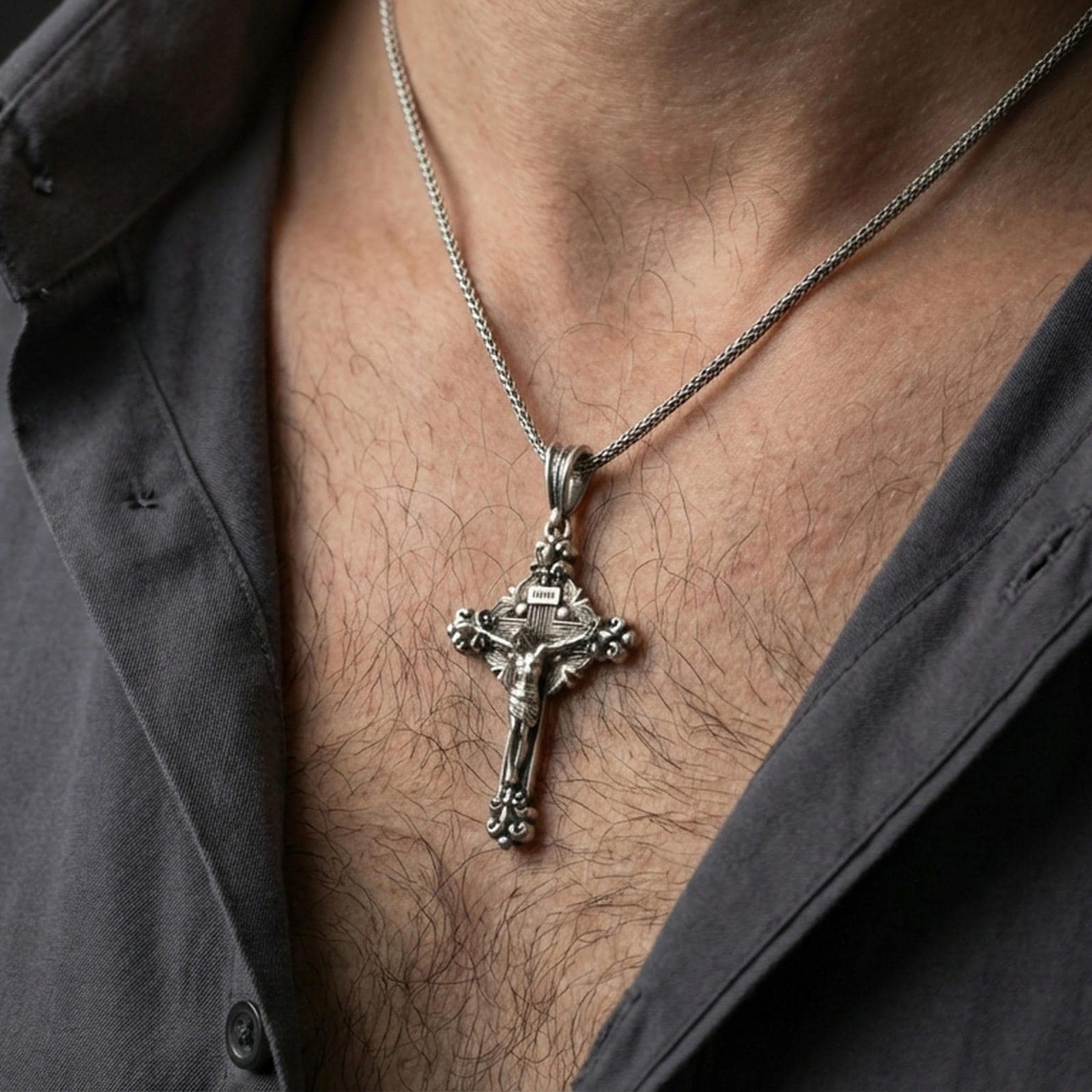 Oxidized crucifix pendant with Jesus figure worn on the neck in a lifestyle jewelry shot, styled against the chest for a bold and devotional look