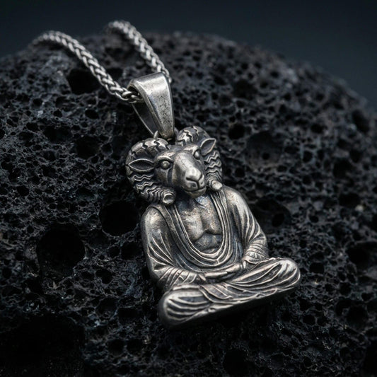 Sterling silver Khnum pendant with an oxidized finish, Egyptian ram-headed deity seated in meditation with detailed robe texture, macro on black volcanic rock