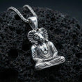 Load image into Gallery viewer, Sterling silver Egyptian god pendant in a polished silver finish, Khnum ram-head meditation figure with sculpted facial details and draped garment, close-up on volcanic stone
