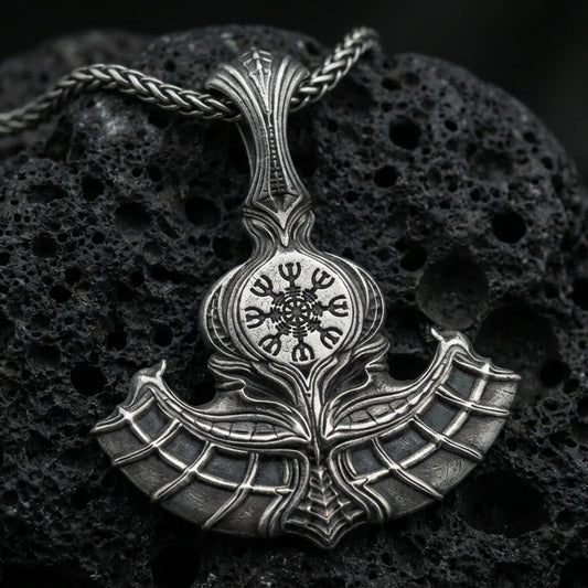 Sterling silver Viking axe pendant with an oxidized finish, detailed double-blade design featuring a Vegvisir compass symbol, close-up on black volcanic rock