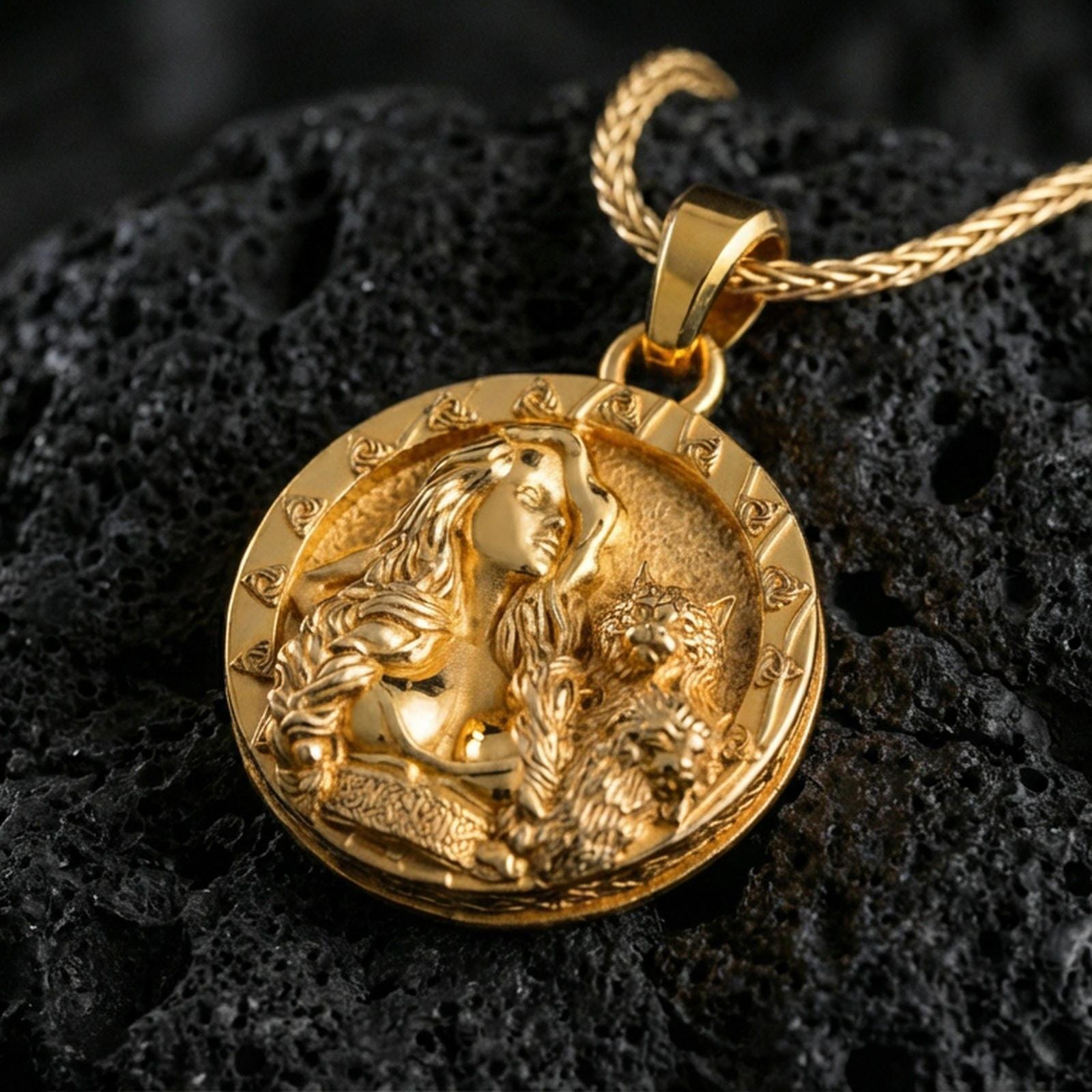 Sterling silver Freya goddess medallion pendant with a gold plated finish, Nordic myth amulet featuring Freya and cat relief, close-up on volcanic rock