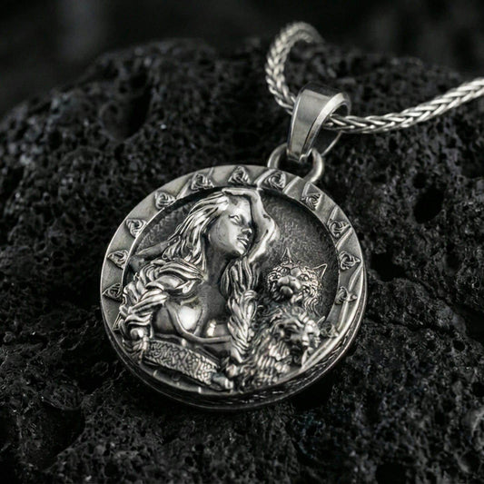 Sterling silver Freya goddess medallion pendant with an oxidized finish, Norse goddess portrait with cat companion relief, close-up on black volcanic rock