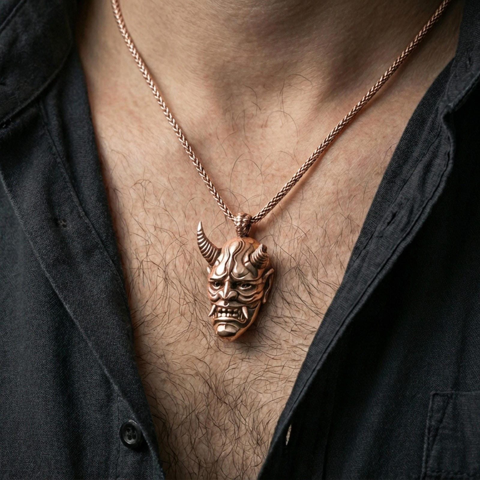 Sterling silver oni mask pendant necklace on the neck, macro lifestyle shot showcasing the rose gold plated finish and carved oni mask features