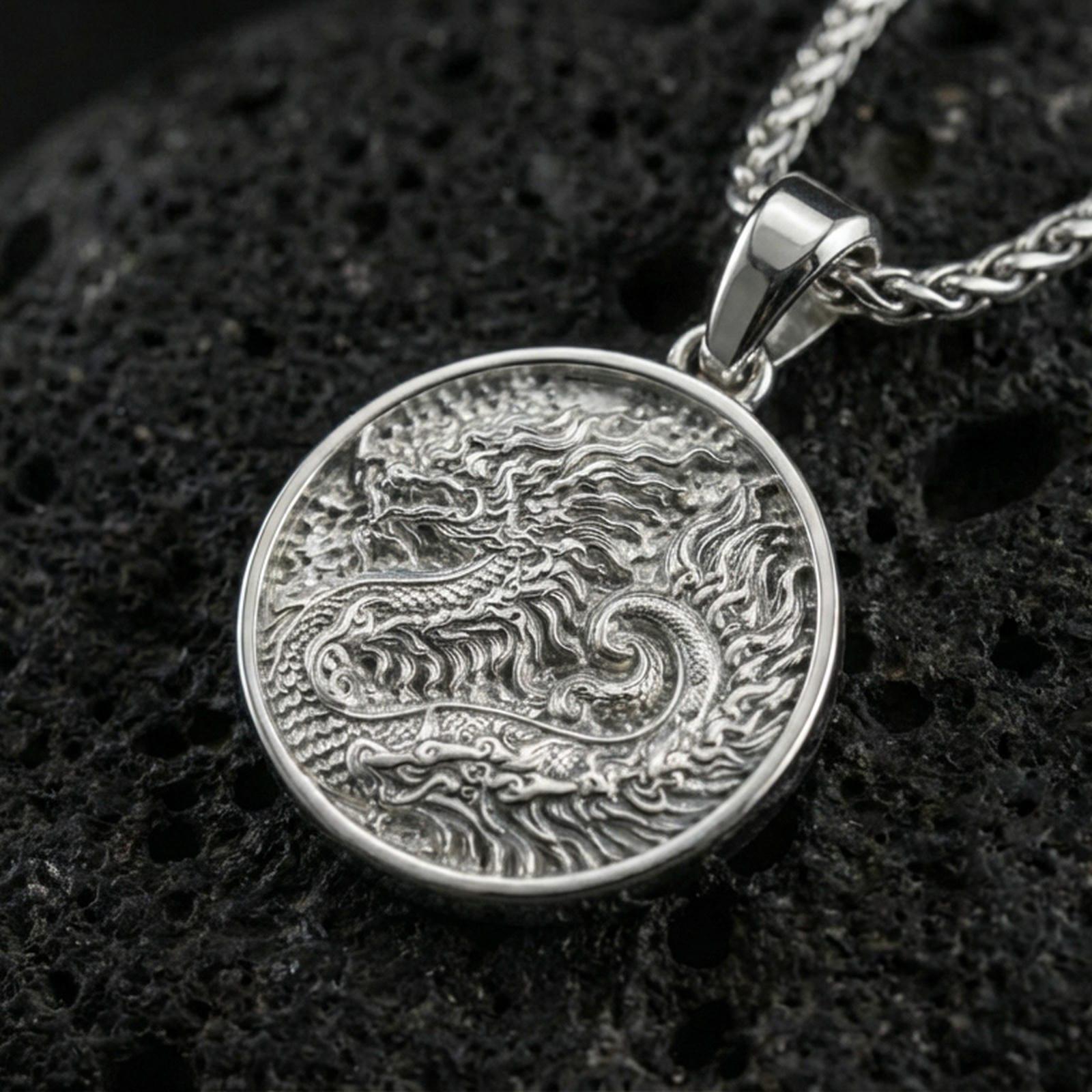 Polished silver round dragon coin pendant necklace on textured volcanic rock, crisp macro product photo emphasizing clean edges and sharp relief detailing.
