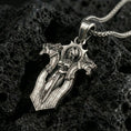Load image into Gallery viewer, Oxidized gothic cross pendant necklace on textured volcanic rock, centered close-up highlighting the armored angel figure, sharp edges, and deep antique contrast.
