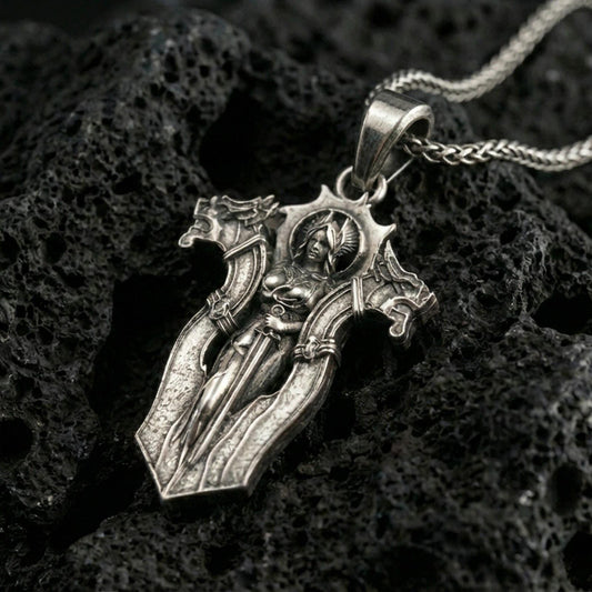 Oxidized gothic cross pendant necklace on textured volcanic rock, centered close-up highlighting the armored angel figure, sharp edges, and deep antique contrast.