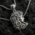 Load image into Gallery viewer, Polished silver Medusa profile pendant necklace on textured volcanic rock, crisp macro product photo emphasizing smooth facial contours, sharp serpent detailing, and clean reflective edges.
