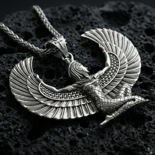 Oxidized winged goddess Isis pendant necklace on textured volcanic rock, centered close-up highlighting the spread wings, feather lines, and deep antique shadowed contrast.