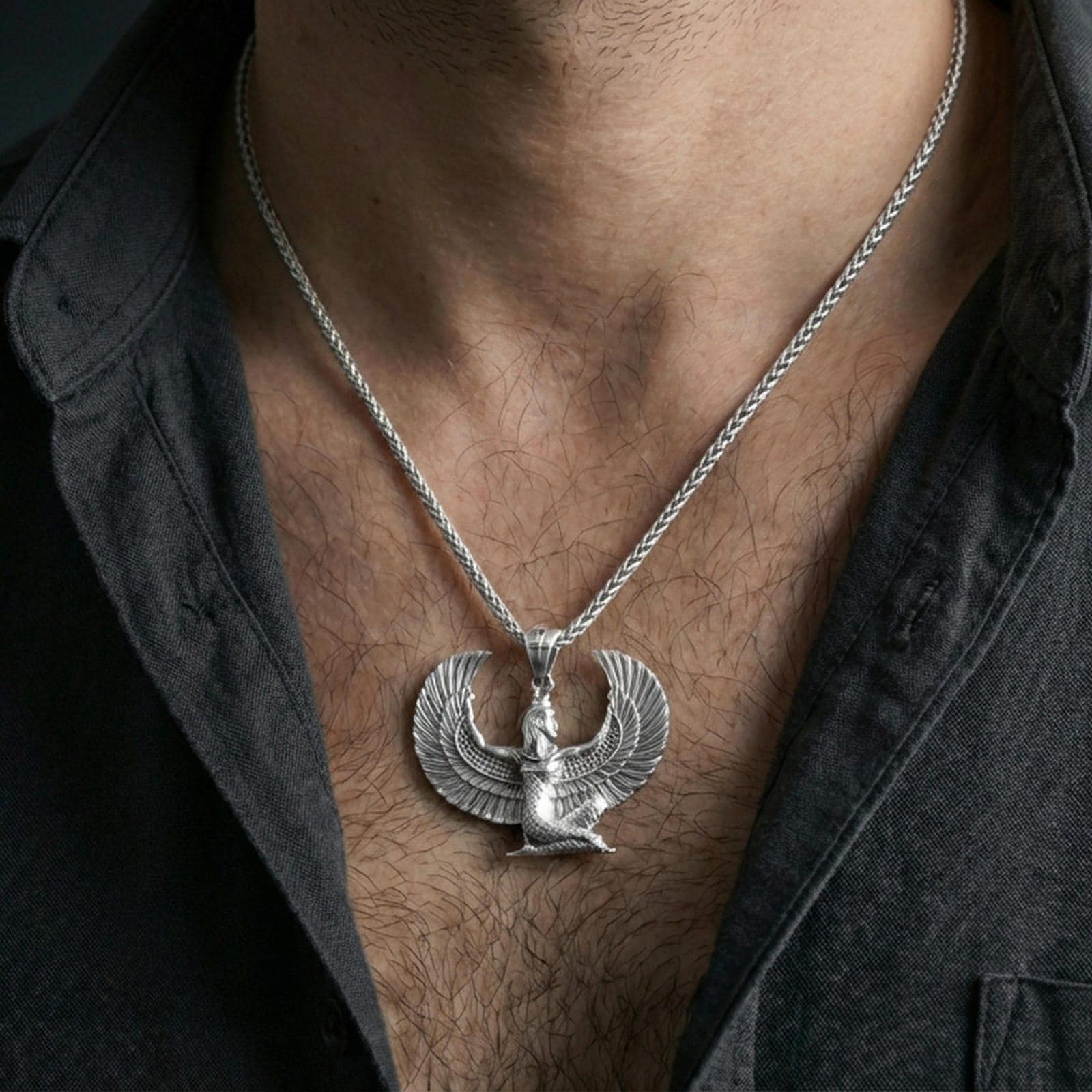 Polished silver winged goddess Isis pendant necklace worn on the neck, clean lifestyle wear shot capturing bright shine and the detailed feather relief in natural light.