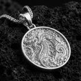 Load image into Gallery viewer, Polished silver dragon medallion pendant necklace on textured volcanic rock, crisp macro product photo emphasizing clean edges, sharp engraving, and detailed flame-and-cloud motifs.
