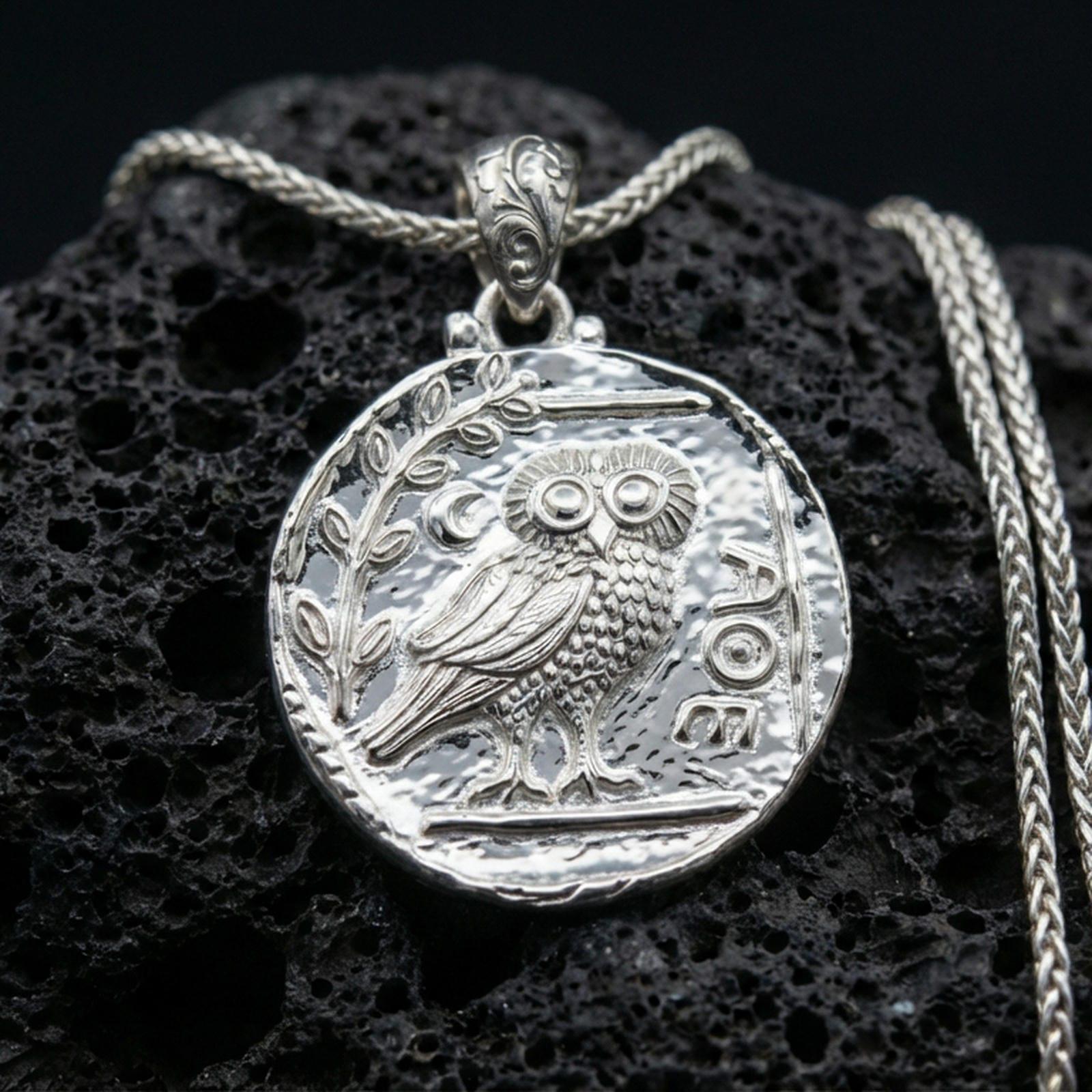 Polished silver owl coin pendant necklace on textured volcanic rock, crisp macro product photo emphasizing clean edges, sharp feather engraving, and bright reflective highlights.