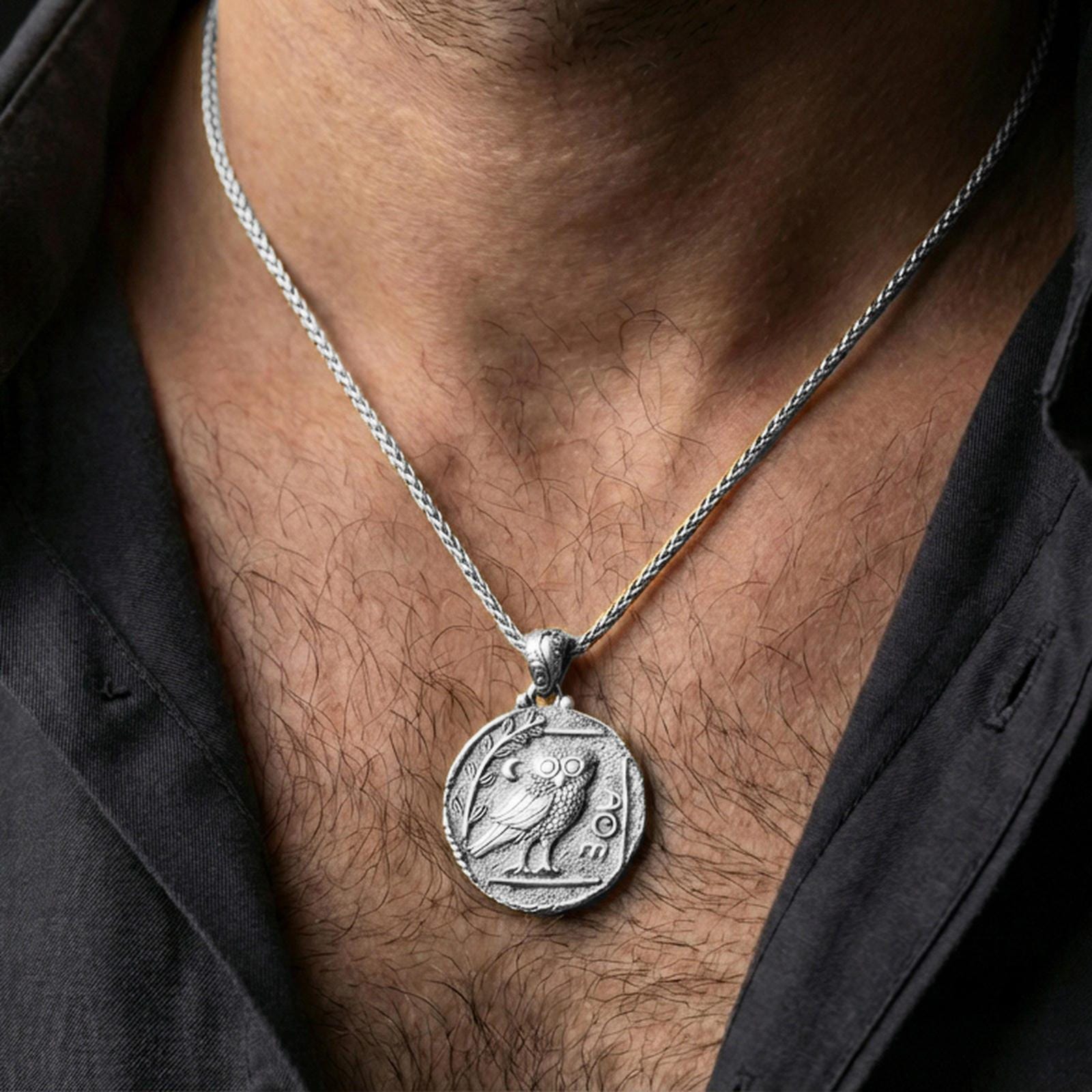Polished silver owl coin pendant necklace worn on the neck, clean lifestyle wear shot capturing bright shine and the owl relief detail in natural light.