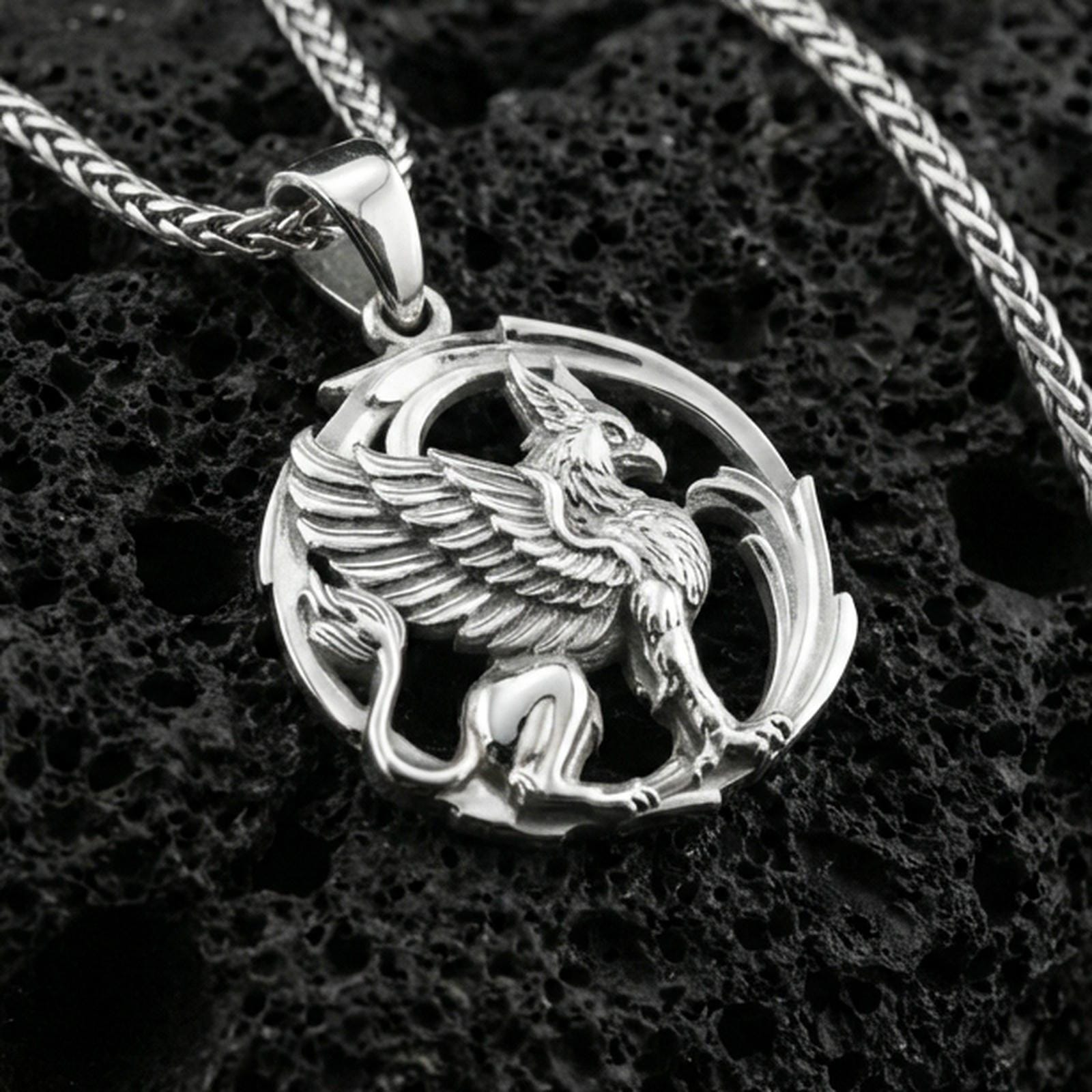 Polished silver griffin pendant necklace on textured volcanic rock, crisp macro product photo emphasizing clean edges, sharp feather lines, and detailed lion body sculpting.