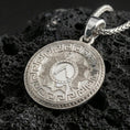 Load image into Gallery viewer, Polished silver Spartan shield medallion pendant necklace on textured volcanic rock, crisp macro product photo emphasizing clean edges, sharp geometric engraving, and bright reflective highlights.
