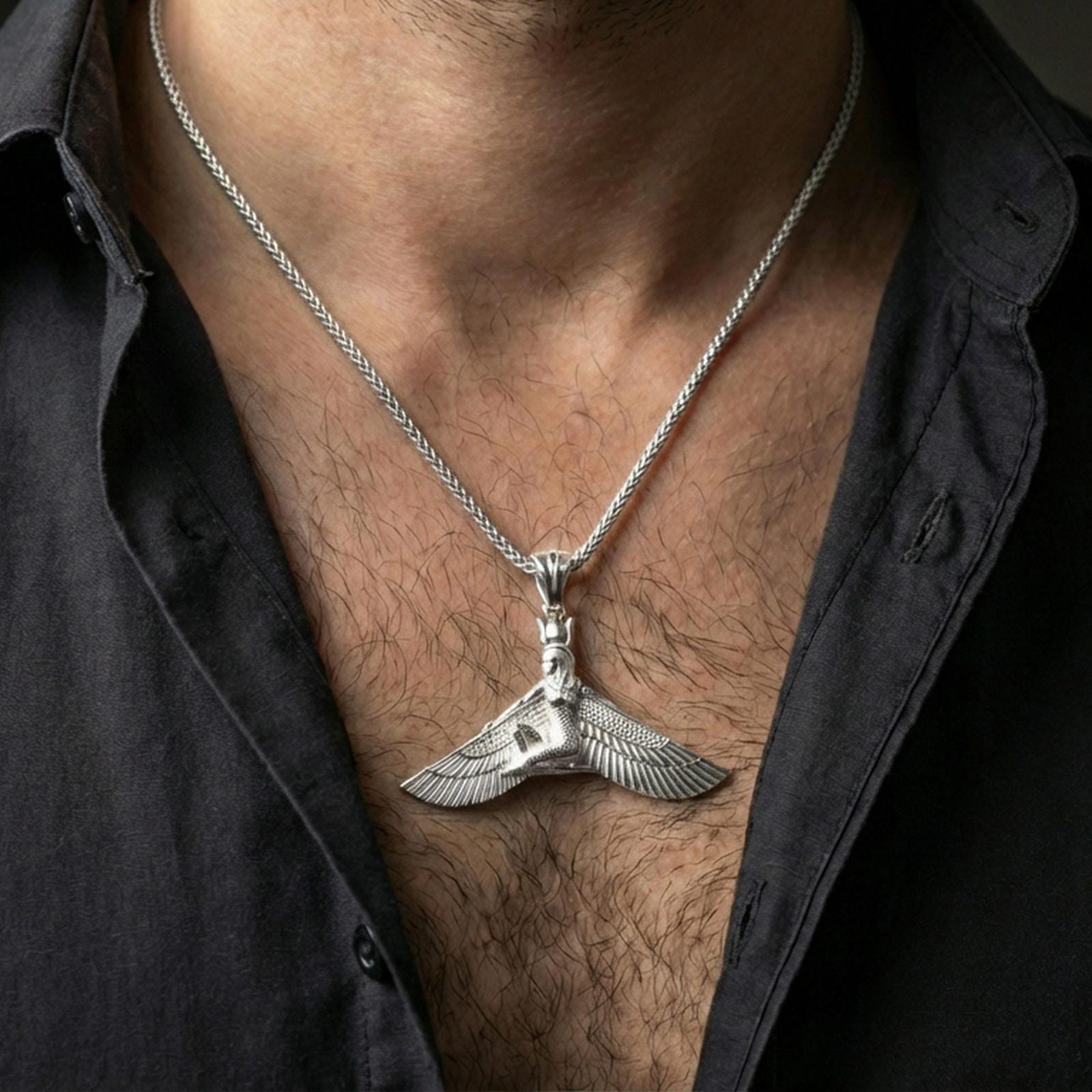 Polished silver winged goddess ankh pendant necklace worn on the neck, clean lifestyle wear shot capturing bright shine and the detailed wing relief in natural light.