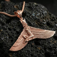 Load image into Gallery viewer, Rose gold plated winged goddess ankh pendant necklace on textured volcanic rock, centered studio-style close-up showcasing soft rosy glow and intricate Egyptian-inspired detailing.
