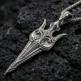 Load image into Gallery viewer, Oxidized Gungnir spear pendant necklace on textured volcanic rock, centered close-up highlighting the carved spearhead details, sharp lines, and deep antique shadowed contrast.
