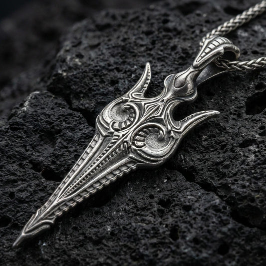 Oxidized Gungnir spear pendant necklace on textured volcanic rock, centered close-up highlighting the carved spearhead details, sharp lines, and deep antique shadowed contrast.