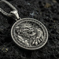 Load image into Gallery viewer, Oxidized imperial guardian lion pendant necklace on textured volcanic rock, centered close-up highlighting the fierce fu dog face, paw detail, and deep antique shadowed contrast within the Greek key frame.
