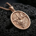 Load image into Gallery viewer, Rose gold plated oval Jesus medal with resurrection scene, cross staff, and detailed sacred relief resting on volcanic rock in an elegant close-up product presentation
