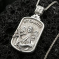 Load image into Gallery viewer, Polished silver Archangel Gabriel medallion with framed devotional portrait, cross staff, and detailed feathered wings placed on textured volcanic rock in a premium studio product shot

