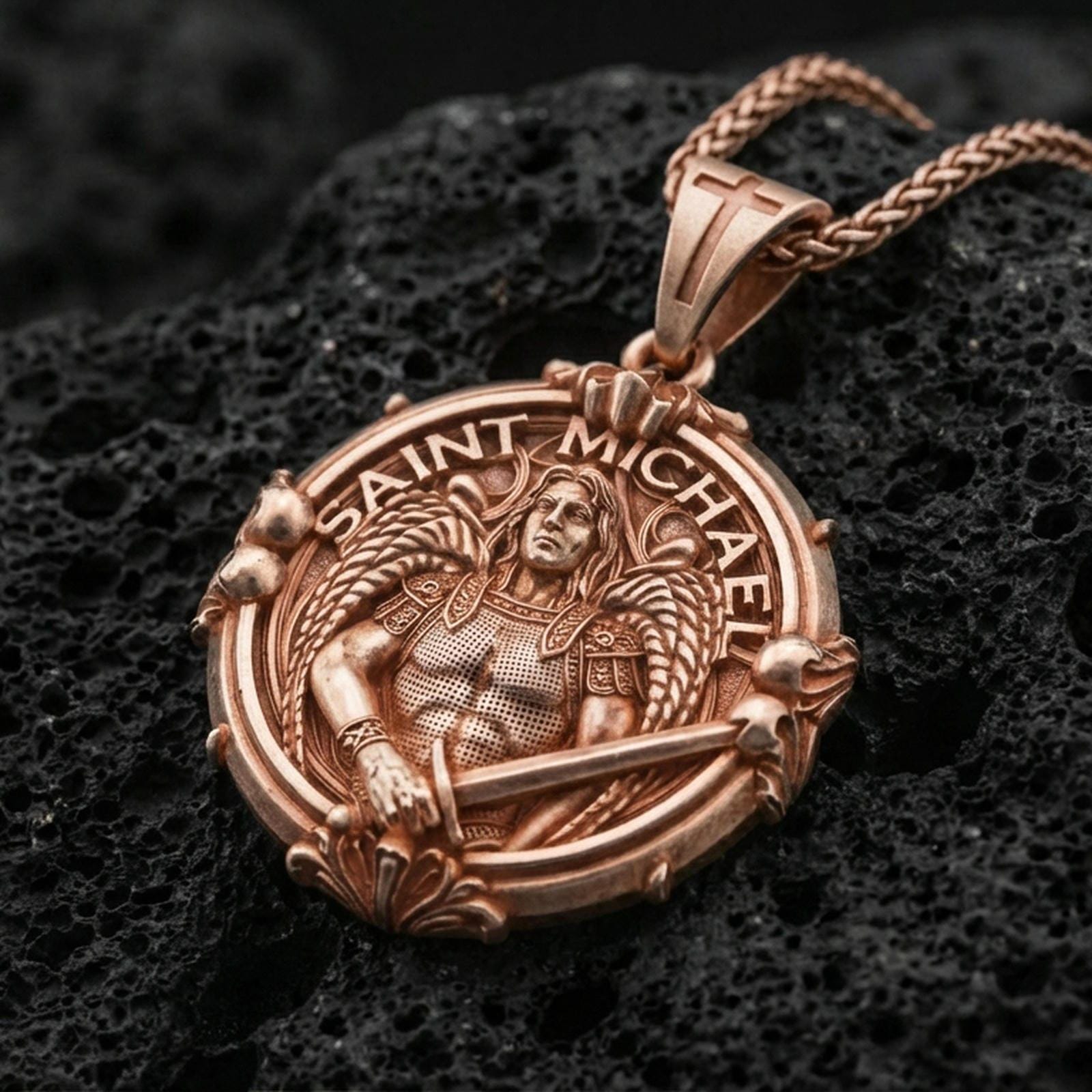 Rose gold plated Archangel Michael pendant with angel warrior portrait, round ornamental frame, and sacred inscription resting on volcanic rock in an elegant close-up product presentation