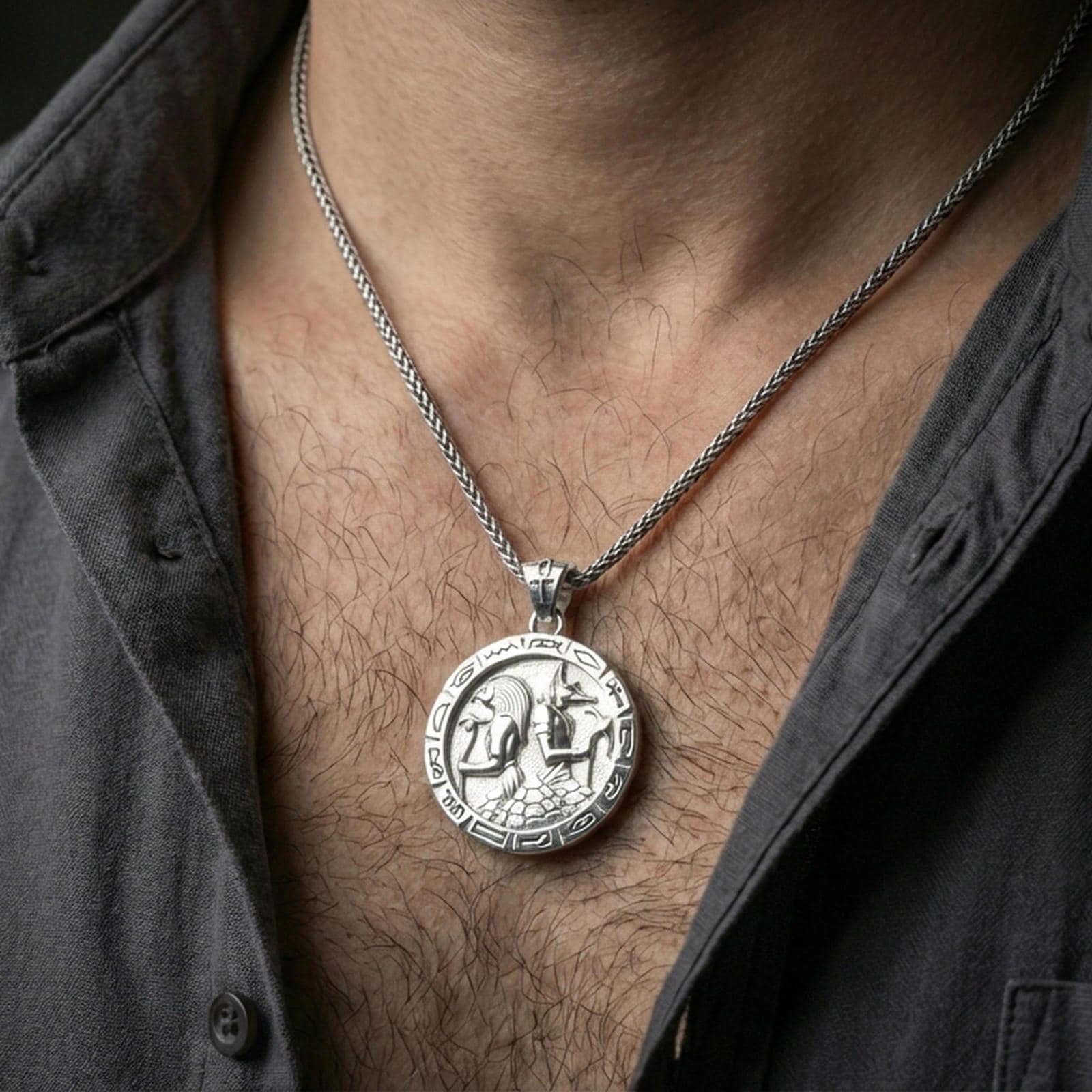 Polished silver Horus and Anubis pendant necklace worn on the neck, clean lifestyle wear shot capturing bright shine and the detailed hieroglyph border in natural light.