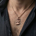 Load image into Gallery viewer, Rose gold plated Hel Norse goddess pendant necklace worn on the neck, lifestyle wear shot with elegant rosy shine and crisp rune-and-portrait detailing visible.
