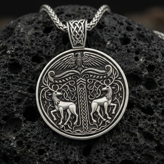 Oxidized Viking deer medallion pendant necklace on textured volcanic rock, centered close-up highlighting the twin stag motif, carved knotwork column, and deep antique shadowed contrast.