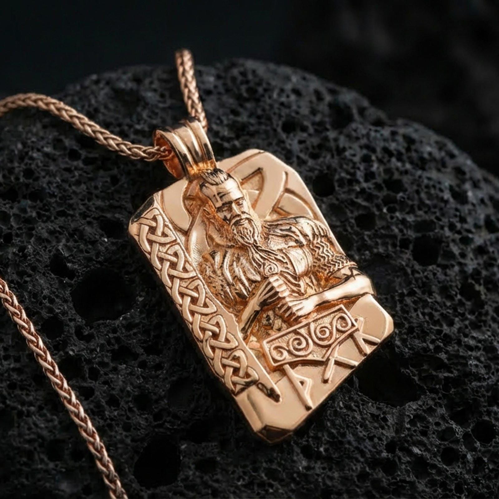 Rose gold plated Thor pendant necklace on textured volcanic rock, centered studio-style close-up showcasing soft rosy glow and intricate Viking knotwork with clear rune accents.